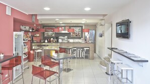 Un área de bar moderna con asientos, una máquina de café y un televisor montado en la pared.