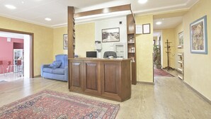 Una zona de recepción con un escritorio de madera, un sofá azul y una alfombra estampada.
