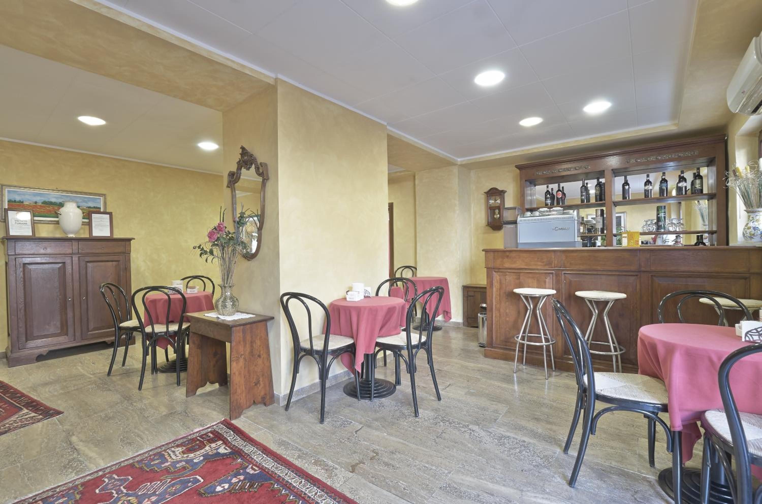 Un ristorante con tavoli e sedie, un'area bar con bottiglie e uno specchio decorativo.