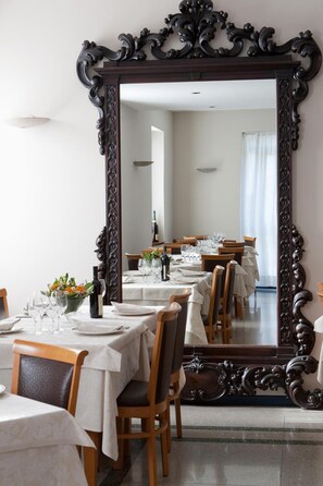 A dining area with tables set for a meal, a large ornate mirror, and a view into the room. - Hotel La Cascata (Azzano San Paolo)