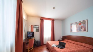 A hotel room with a bed, a desk with a computer, a chair, a television, and a painting on the wall. - Hotel La Cascata (Azzano San Paolo)