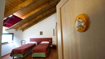 Una stanza con due letti, un soffitto in legno e una sveglia a muro.