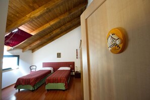 Una habitación con dos camas, techo de madera y un reloj de pared.