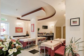 Un comedor de hotel con mesas redondas, sillas y una barra.