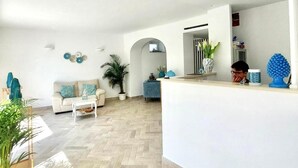 A spacious living area with a herringbone floor, a sofa, a coffee table, and a potted plant. - Hotel Guarracino (Capri)