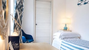 A hotel room with a bed, a desk with a laptop, a nightstand with a lamp, and a window with curtains. - Hotel Guarracino (Capri)