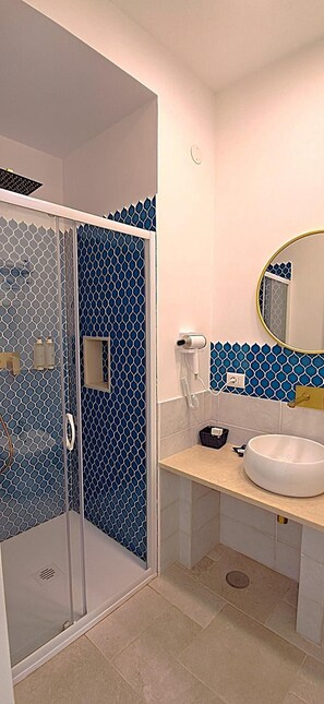 A bathroom with a glass shower enclosure, a sink, a mirror, and a hairdryer. - Hotel Guarracino (Capri)
