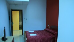 Una habitación pequeña con cama, escritorio y televisor.