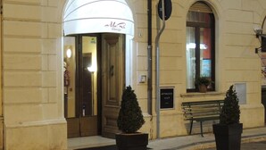 Ein Hotel mit Eingangsbereich, einer weißen Markise, einer Bank und zwei Blumentöpfen.