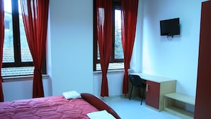 Ein Schlafzimmer mit Bett, Schreibtisch, Stuhl und Fernseher.