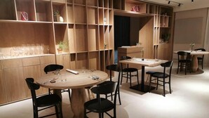 A modern dining area with round tables and black chairs, surrounded by wooden shelving units. - Franco Il Conte (Bagheria)