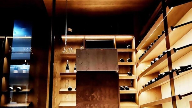 A modern interior with wooden shelving units and a central wooden podium. - Franco Il Conte (Bagheria)