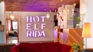 A hotel lobby with a red sofa, a reception desk, and a sign that reads 'HOTEL ELF RIDA.' - Frida Am Wald (Rasun Anterselva)
