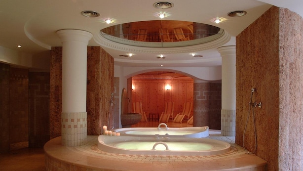 A spa area with a circular hot tub, a wooden bench, and a glass-enclosed upper level. - Frida Am Wald (Rasun Anterselva)