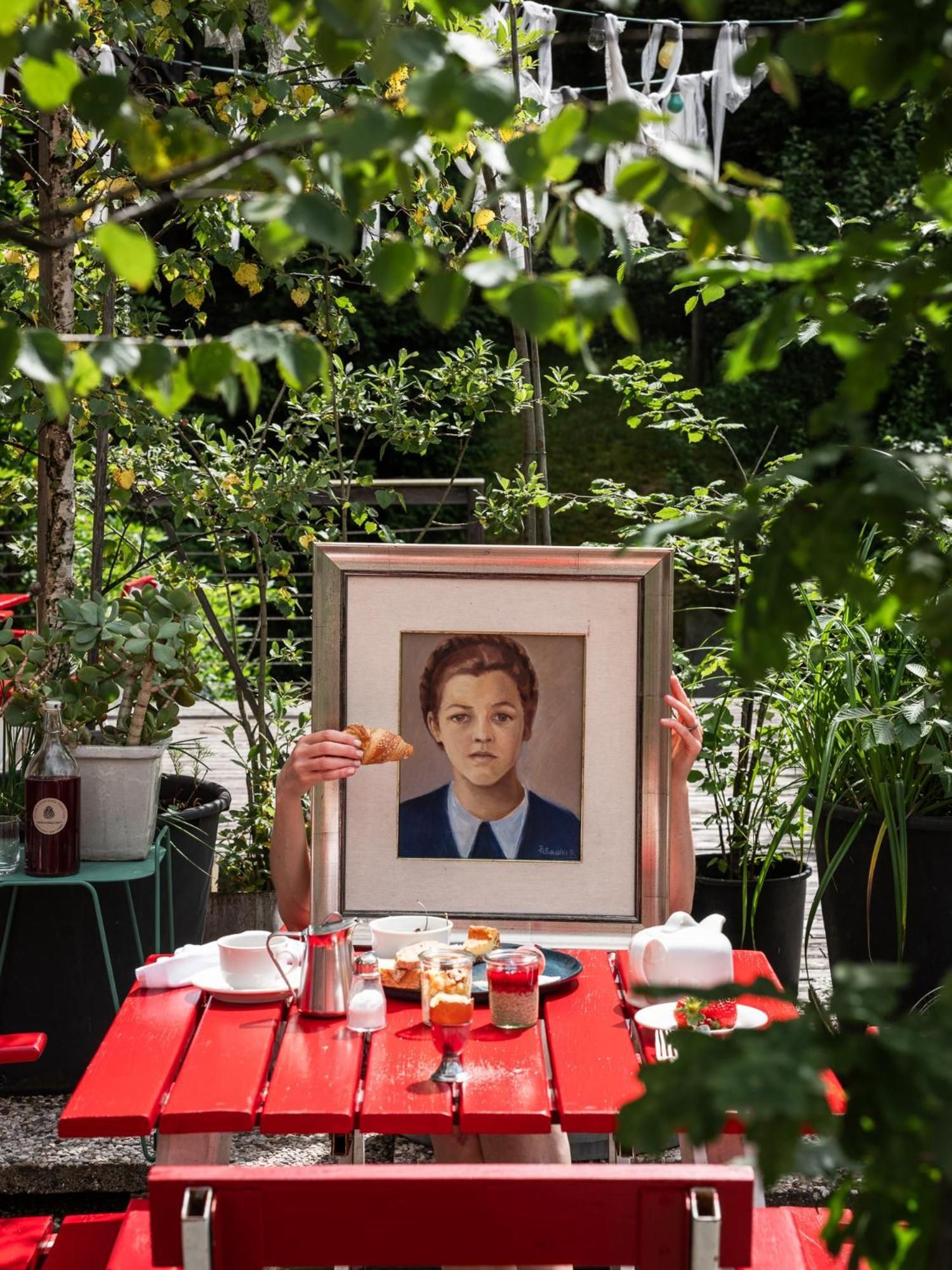Mesa al aire libre con un retrato enmarcado, un croissant y diferentes alimentos.