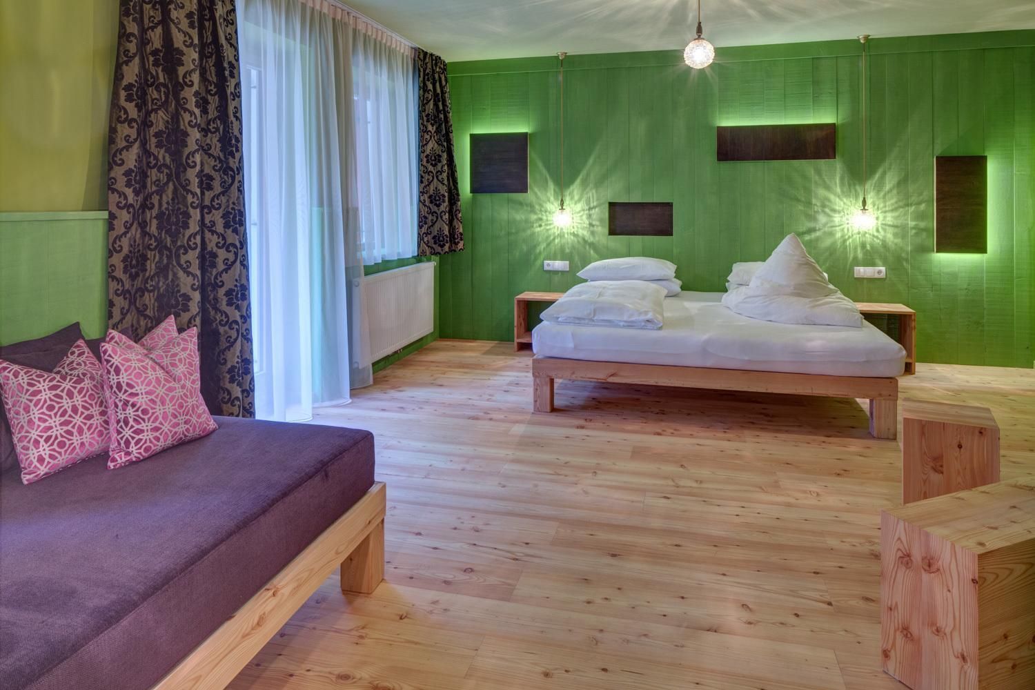 Una habitación con cama, sofá y ventana con cortinas.