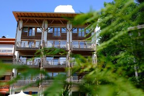 A multi-story building with balconies and a reflection in the water. - Frida Am Wald (Rasun Anterselva)