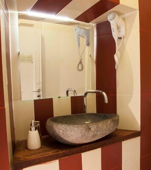 A bathroom with a stone sink, a mirror, a hairdryer, and a soap dispenser. - Albergo Delle Spezie (La Spezia)