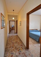 Un pasillo con suelo de baldosas que lleva a un dormitorio con cama.