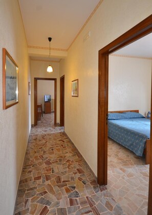 Un pasillo con suelo de baldosas que lleva a un dormitorio con cama.