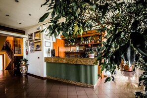 Zona de bar con mostrador, estantes llenos de botellas y cuadros en la pared.