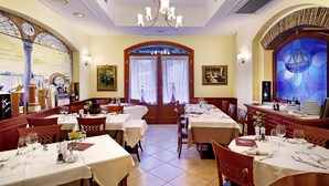 Un restaurante con varias mesas, una araña y un vitral.