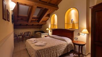 A bedroom with a wooden ceiling, a bed with a headboard, two bedside tables with lamps, a chair, and a small table with a lamp.