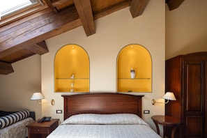 A bedroom with a wooden ceiling, a bed with a white quilt, two bedside tables with lamps, and a nightstand with a telephone. - Locanda La Comacina (Comacchio)