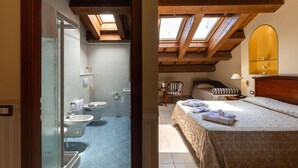Un dormitorio con cama, mesita de noche, espejo y tragaluz.