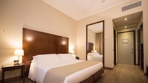 A hotel room with a large bed, bedside tables, a mirror, and a door leading to another room. - Hotel Motel Ascot (Lissone)