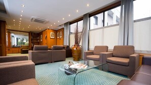 A modern living room with sofas, a coffee table, and a large window. - Hotel Motel Ascot (Lissone)