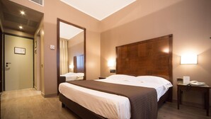 A hotel room with a large bed, a wooden headboard, a bedside table with a phone, and a mirror on the wall. - Hotel Motel Ascot (Lissone)