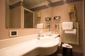 Un baño con una bañera grande, un lavabo, un espejo, un perchero para toallas y un secador de pelo.