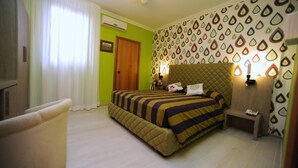Hotellihuone, jossa on sänky, tuoli, yöpöytä ja seinä, jossa on geometrinen kuvio.