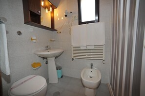 A small bathroom with a toilet, bidet, sink, and a mirror above the sink. - Hotel Tropical (Ostuni)