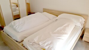 A single bed with white bedding in a room with a wooden headboard and a nightstand. - B&b Hotel Dolomiti (Bolzano)