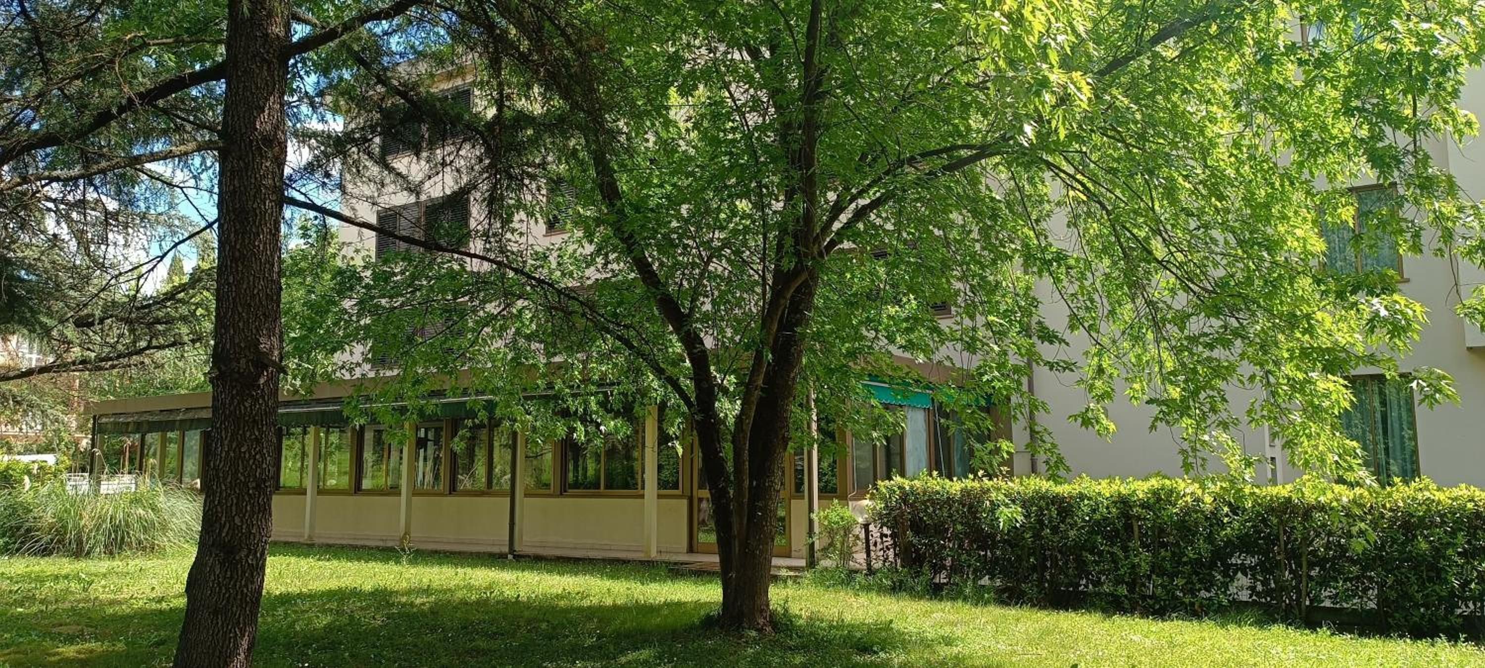 Un edificio con facciata in vetro, circondato da alberi e un prato curato.
