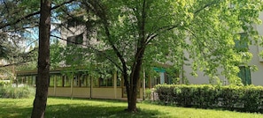 A building with a glass facade, surrounded by trees and a well-maintained lawn. - Park Hotel Galileo (Reggello)