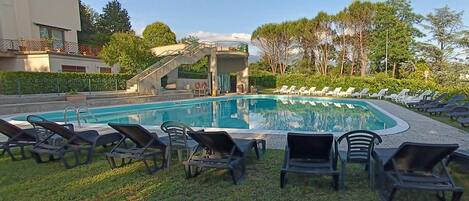 A swimming pool with lounge chairs and a staircase leading to a covered area.