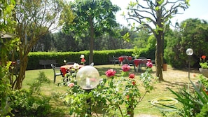 An outdoor garden with tables and chairs, surrounded by greenery and flowering plants. - Park Hotel Galileo (Reggello)