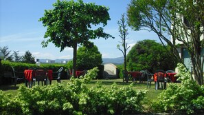 An outdoor seating area with tables and chairs, surrounded by greenery and a view of distant mountains. - Park Hotel Galileo (Reggello)