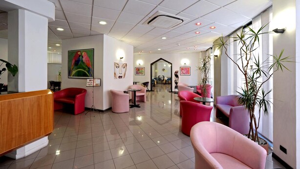 A hotel lobby with a reception desk, seating areas, and artwork on the walls. - Tuscia Hotel (Viterbo)