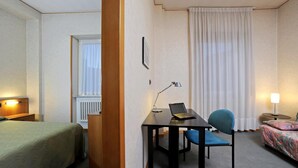 A hotel room with a bed, a desk with a laptop, a chair, and a bedside table with a lamp. - Tuscia Hotel (Viterbo)
