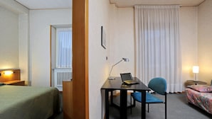 A hotel room with a bed, a desk with a laptop, a chair, and a bedside table with a lamp. - Tuscia Hotel (Viterbo)