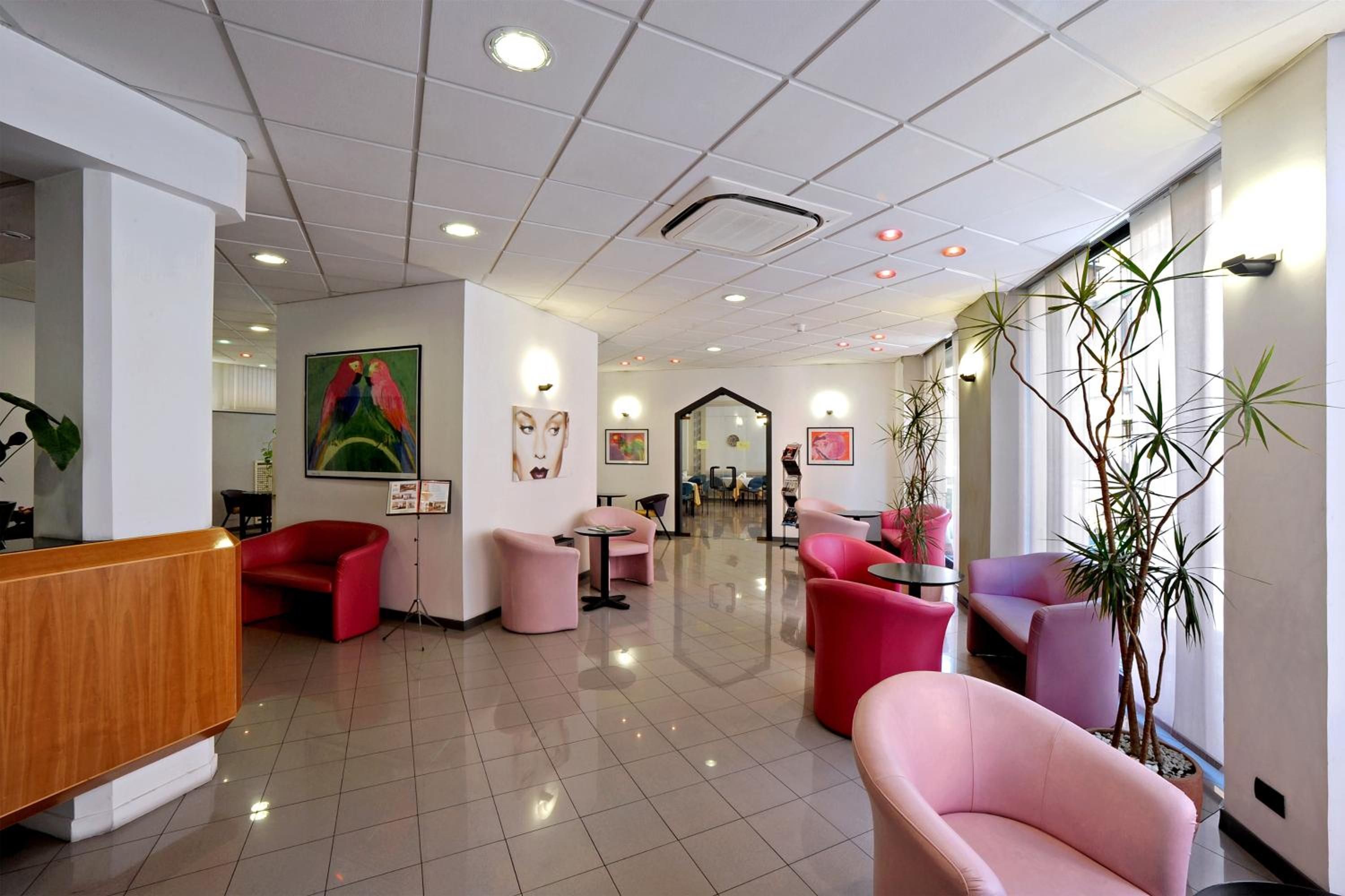 A hotel lobby with a reception desk, seating areas, and artwork on the walls.