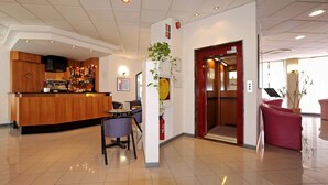 A hotel lobby with a reception desk, a bar area, and a dining space. - Tuscia Hotel (Viterbo)