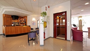 A hotel lobby with a reception desk, a bar area, and a dining space. - Tuscia Hotel (Viterbo)