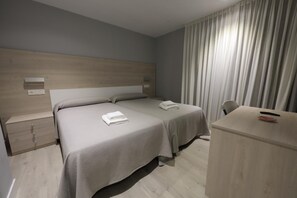 A hotel room with a bed, bedside tables, a desk, and a chair.
