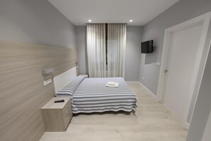 A modern bedroom with a bed, bedside table, and a TV mounted on the wall. - Hotel Goizalde (Sopelana)
