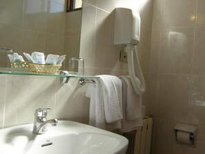 A bathroom with a white sink, a glass shelf with toiletries, a towel rack, and a hand dryer.